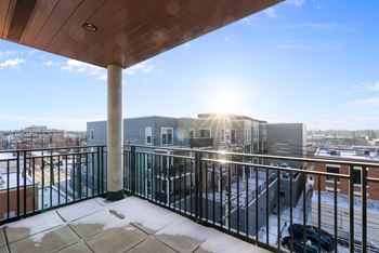 A balcony with a black railing and a concrete pillar.